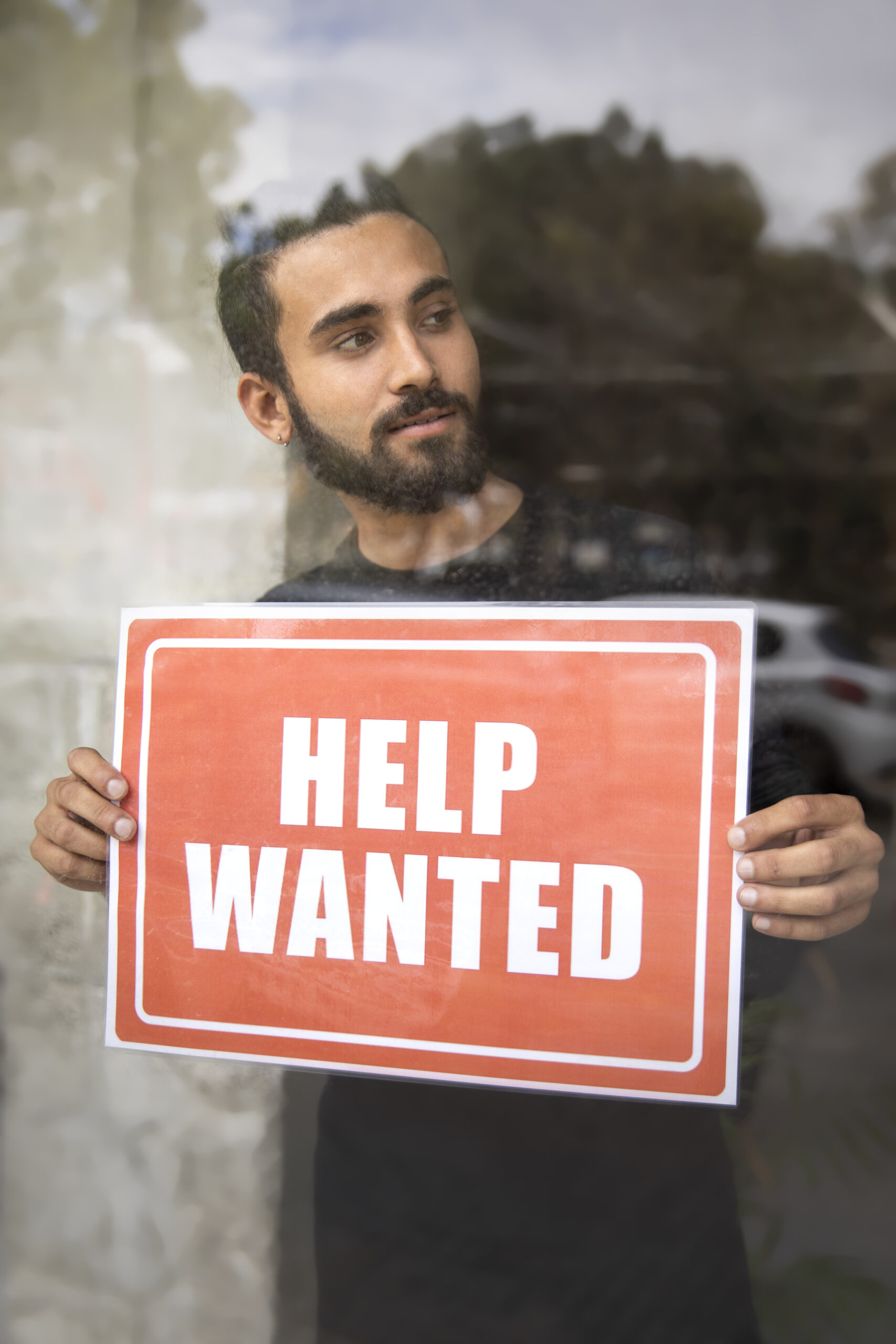Person With Hiring Sign By Window Scaled
