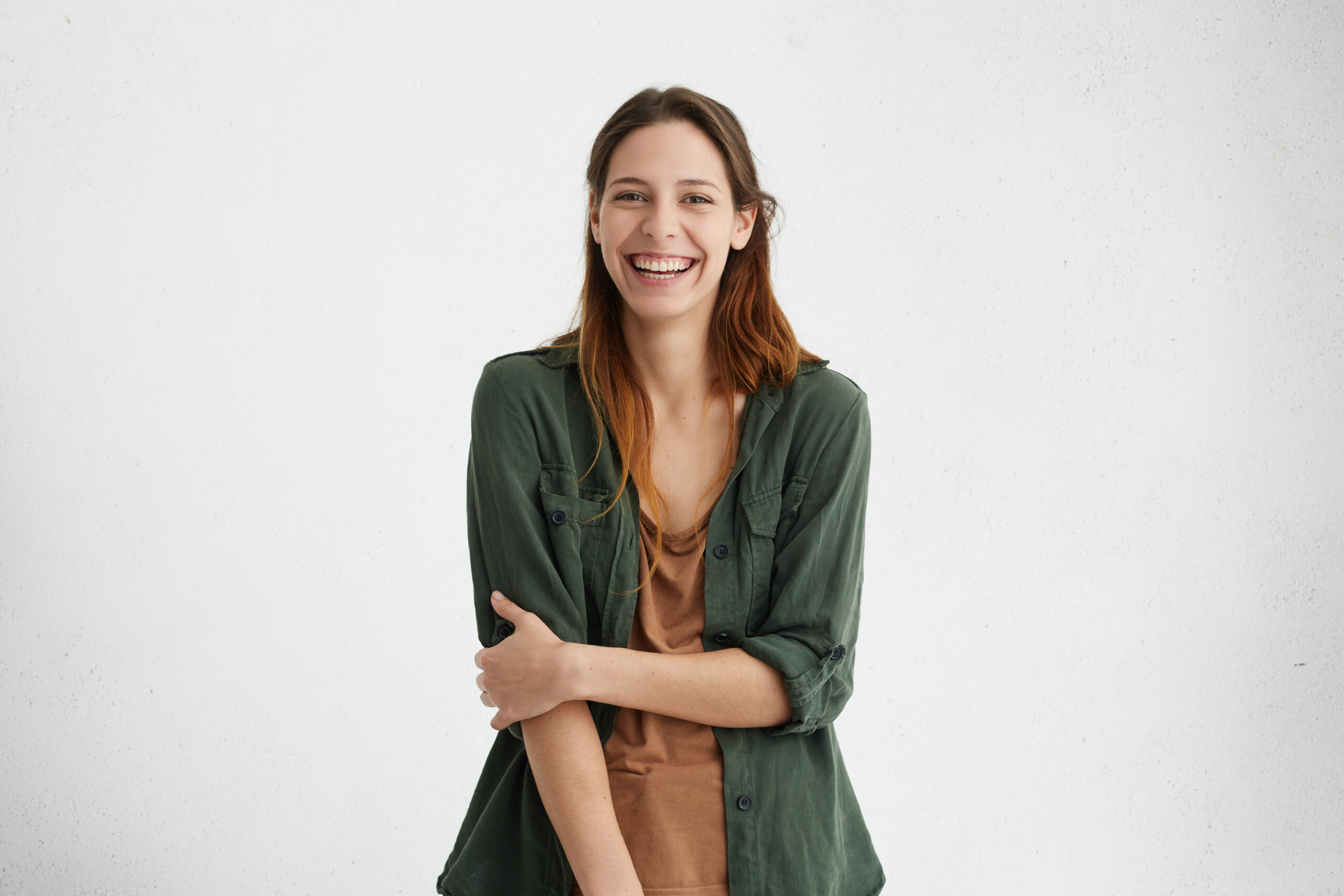 people, beauty and lifestyle concept. shot of attractive sensual woman with wide smile dressed in green jacket and brown t shirt smiling broadly being happy to meet her best friend. joyful nice female